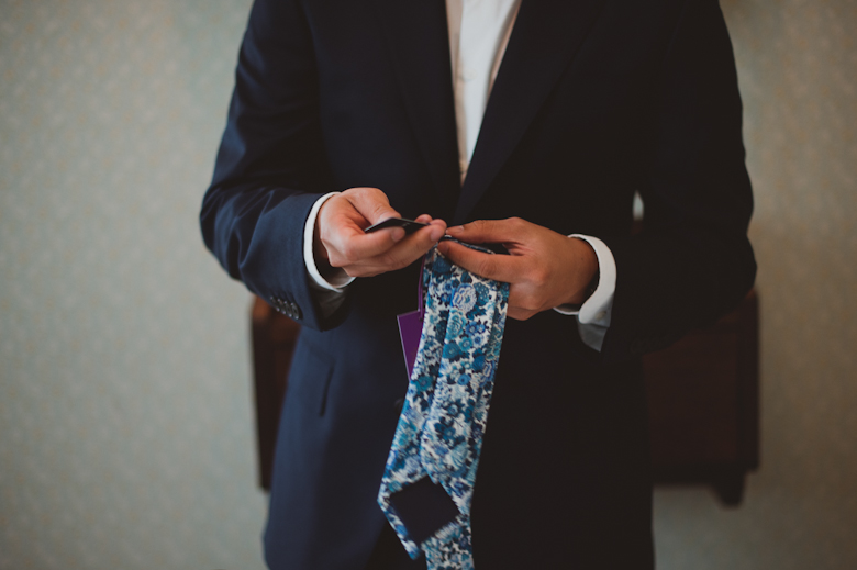 Groom getting ready putting the tie on