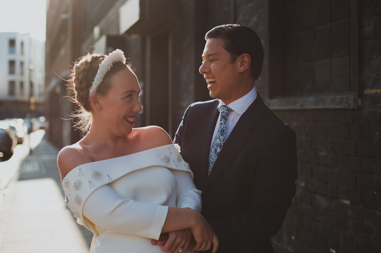 Bride and groom laugh outside the Bistrotheque, East London Wedding