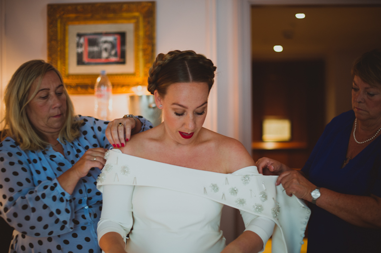 mum and aunt helping bride with baby bump getting ready in her 50's dress