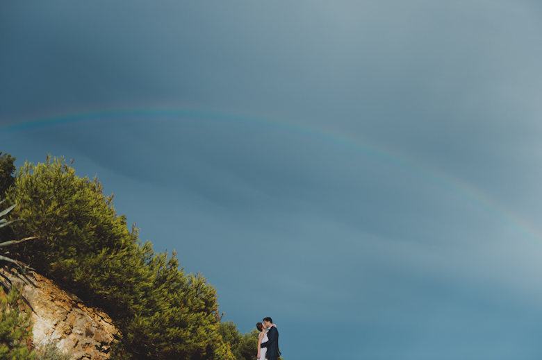 bride and groom with the seaside, rainbow and pine trees