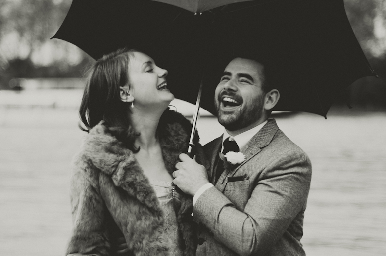 Bride and groom laugh on a rainy wedding day, London