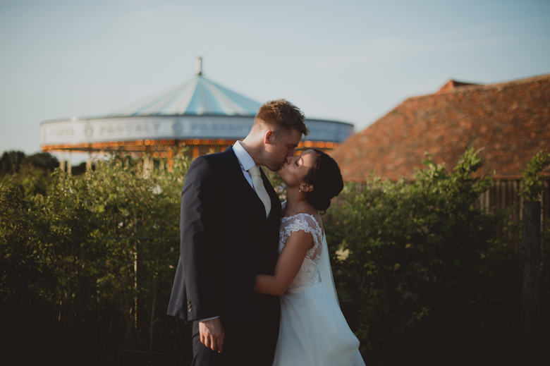 bride and groom kiss outside the carousel at the preston court wedding venue - Sasha Weddings - Kent wedding photographer