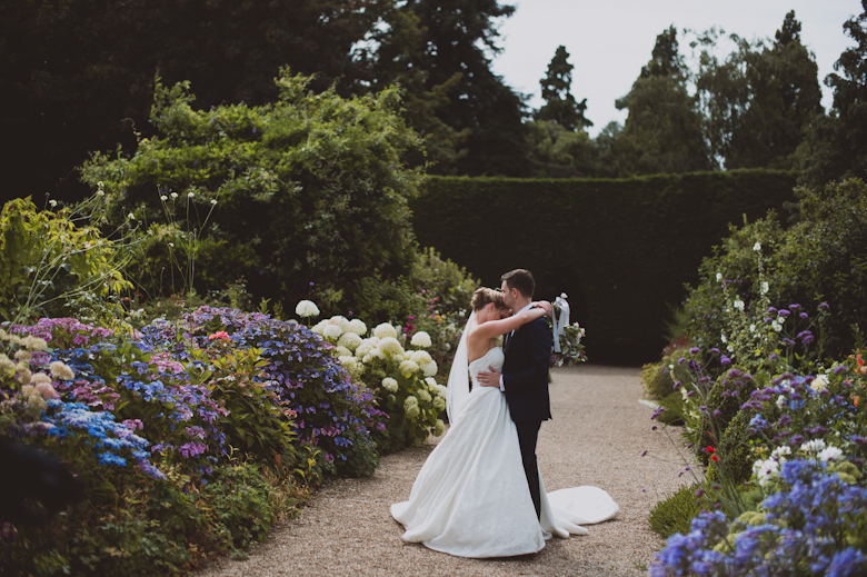 Wedding Photographer Sussex - bride and groom hugging in a garden